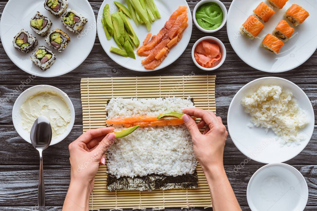 Ingredienti per sushi disposti accanto a un tappetino di bambù.