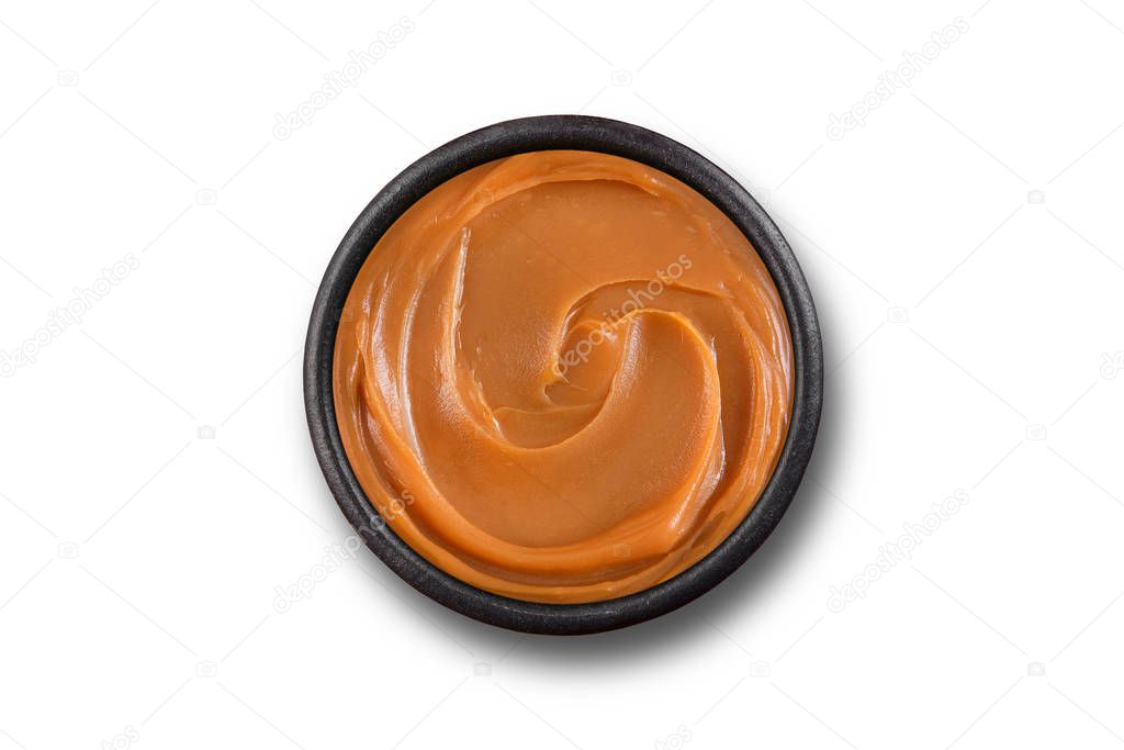 Barattolo di dulce de leche con cucchiaio su un tavolo.