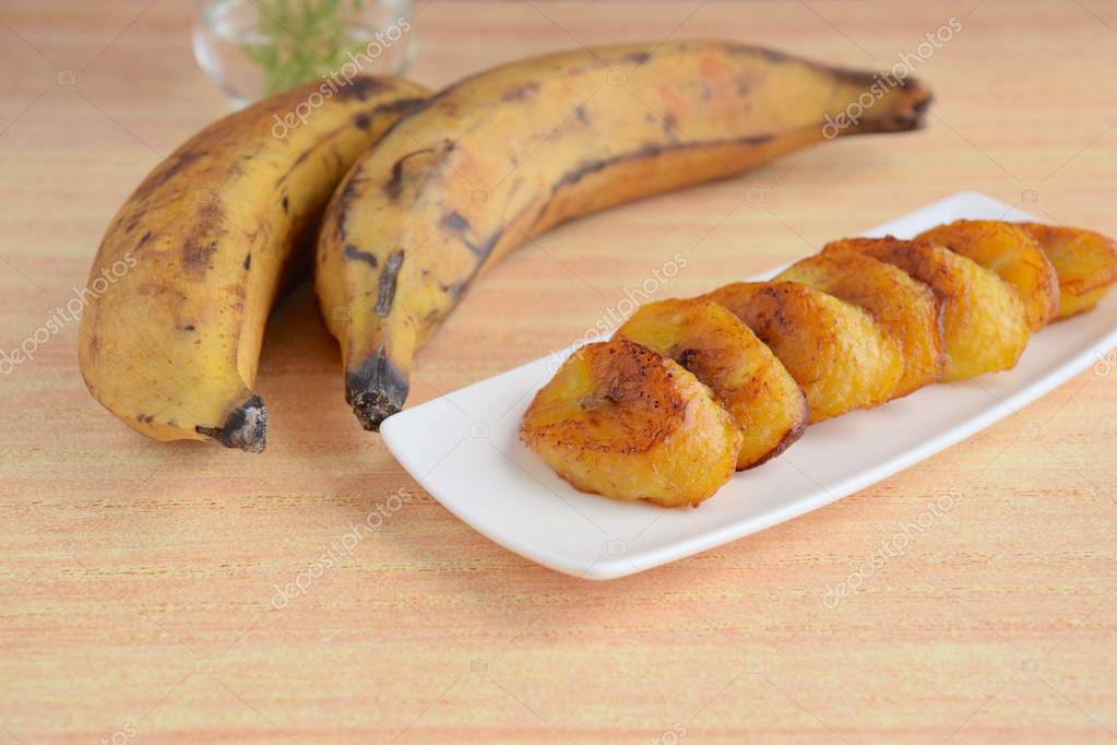 Platani maturi con buccia gialla e nera appoggiati su un banco.