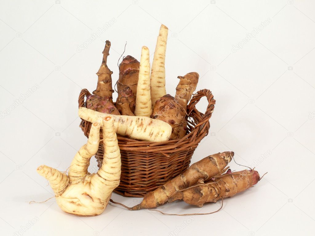 Radici e tuberi misti esposti in cassette di legno.